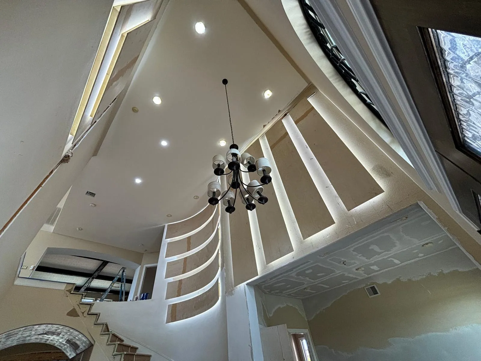 Two-story foyer remodel with chandelier and LED-backlit staircase wall
