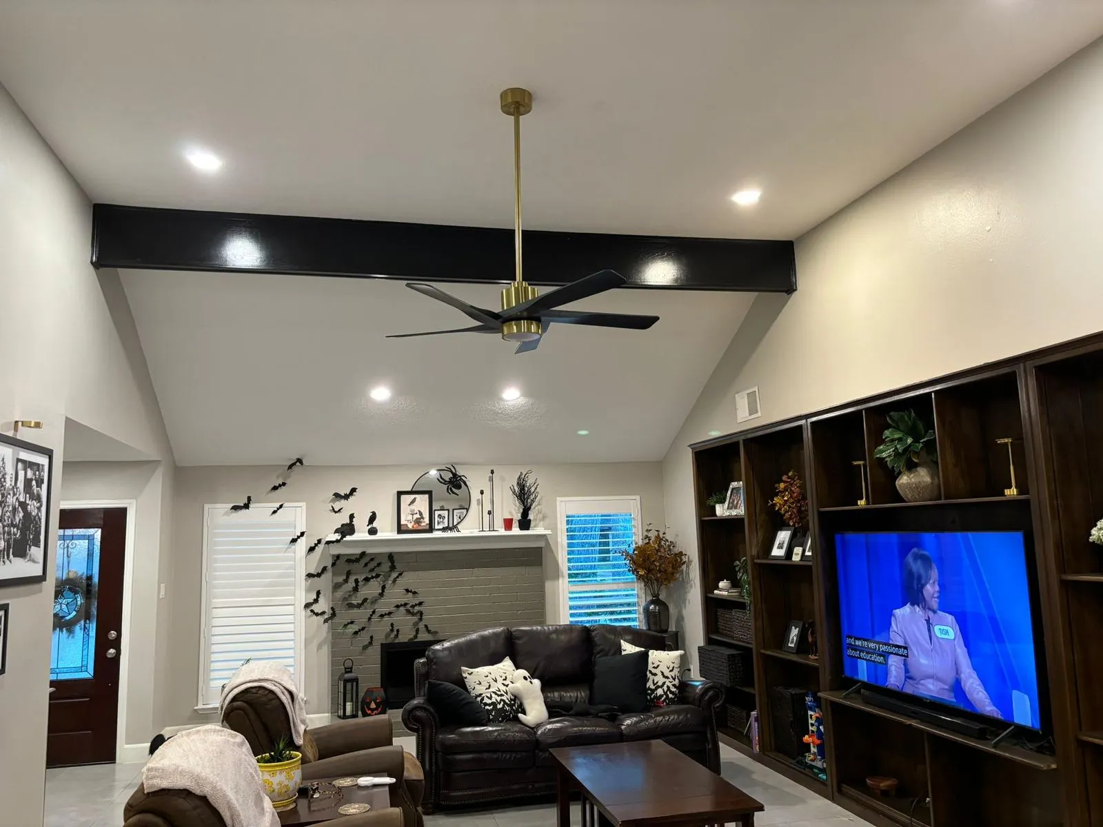 Remodeled vaulted living room with painted beams, brass fan and built-ins