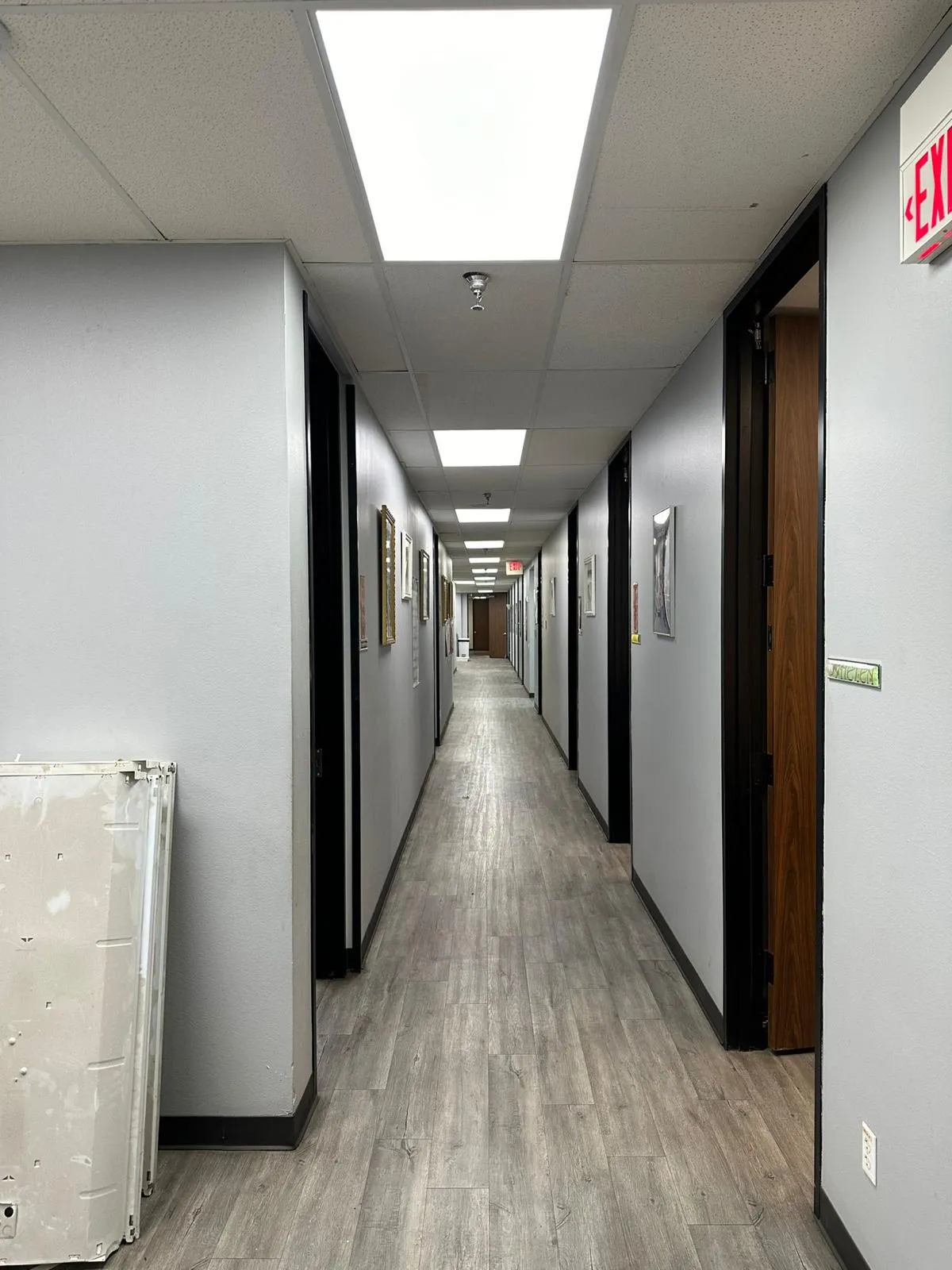 Renovated office corridor with new vinyl plank flooring and panel lighting