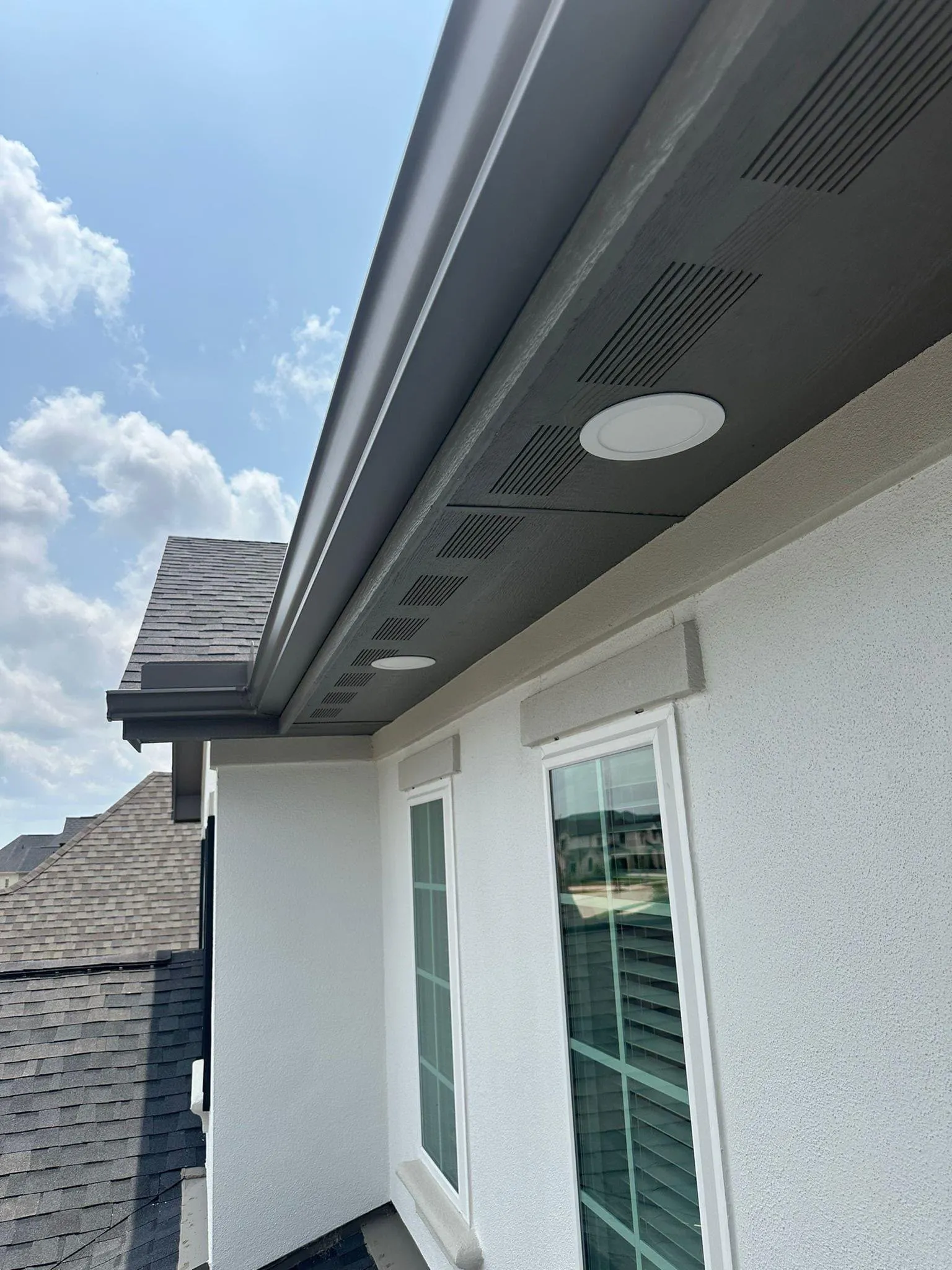New recessed LED soffit lights under the eave of a stucco home