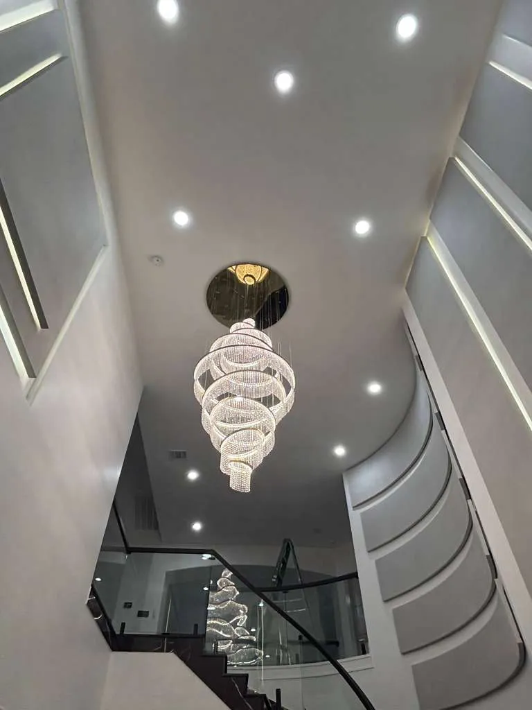 Spiral crystal chandelier above a curved staircase in a two-story foyer